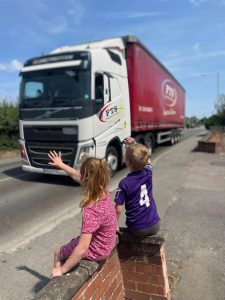 image of children waving to a truck as it drives by